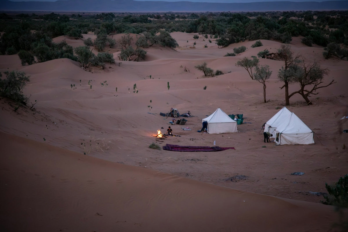 Desert camp with tents and campfire at campfire at campfire