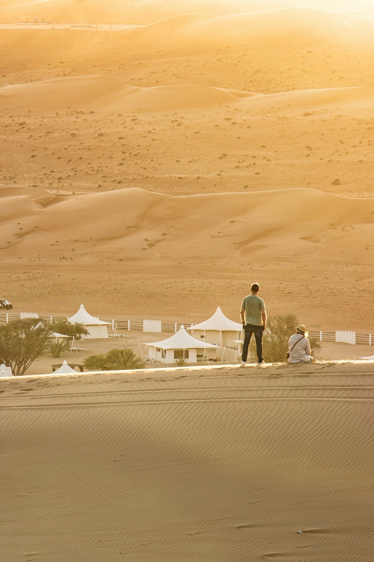 People watching a desert camp from a golden sand dune