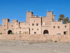 Historic mudbrick kasbah with detailed geometric patterns and towers under clear blue sky in Morocco