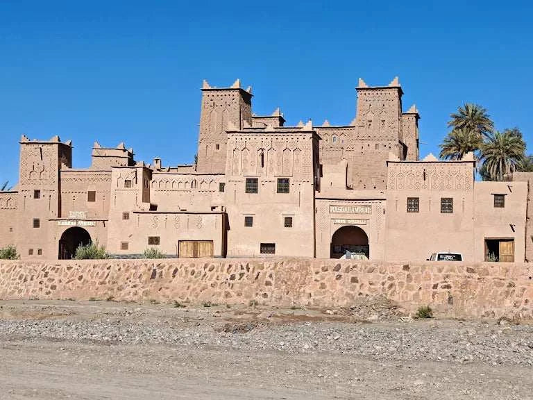 Historic mudbrick kasbah with detailed geometric patterns and towers under clear blue sky in Morocco