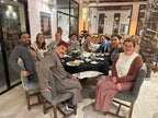Group of people dining together around a black tablecloth-covered table with plates and drinks in a hotel restaurant, illustrating the 2 day tour from Merzouga to Marrakech experience.