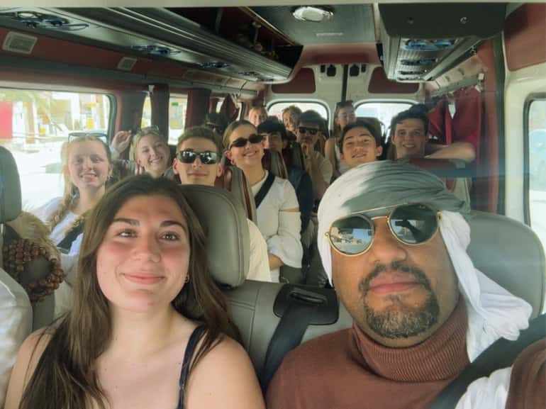 Group of diverse tourists inside a bus enjoying the 2 day tour from Merzouga to Marrakech, smiling and relaxed.