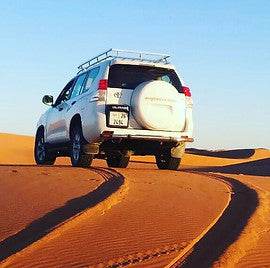 White off-road SUV driving on sandy dunes of the Sahara desert during a 3-Day Tour from Ouarzazate to Merzouga and Zagora
