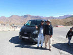 Black Ford van parked on desert road with two men standing in front under clear blue sky on a 3 Days Tour.
