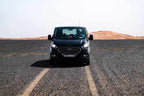 Black Ford passenger van driving on a gravel road toward sand dunes in the distance, illustrating the 3 Days Tour adventure.