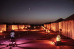 Desert camp at night with illuminated tents and decorative lanterns lining a sandy pathway under a crescent moon sky, perfect for a 4-day desert tour