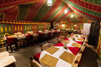 4-day desert tour dining tent with long tables covered in red and white cloths, wicker placemats, and traditional colorful fabric decor
