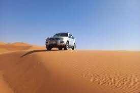 4x4 Rental in Merzouga silver four-wheel drive vehicle on orange desert sand dunes under clear blue sky