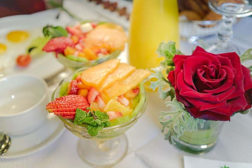 Agadir Beach Club Hotel breakfast table with fresh fruit salad in glass bowls, a red rose in a vase, and white crockery