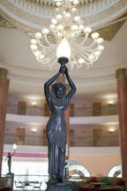 Dark bronze statue of a woman holding a glowing lamp above her head inside Agadir Beach Club Hotel's ornate interior