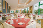 Spacious Agadir Beach Club Hotel dining area with white and red patterned tablecloths, beige chairs, and neatly arranged white napkins