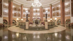 Spacious hotel lobby with tall brown columns, elegant chandeliers, classical statues, and ornate patterned flooring at Agadir Beach Club Hotel