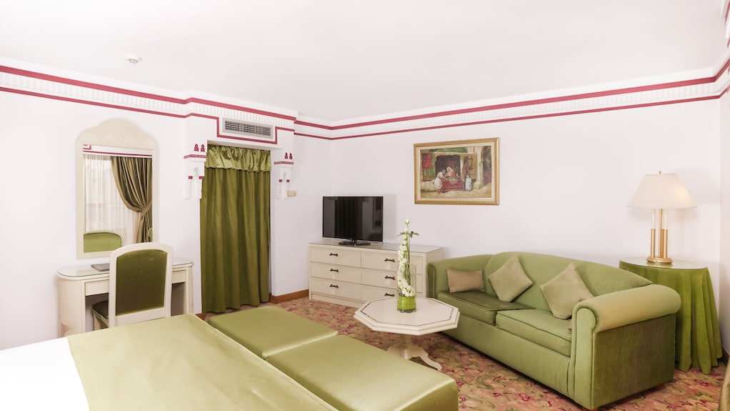 Agadir Beach Club Hotel room with green velvet sofa, matching curtains, white walls, and a vanity mirror