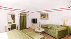 Agadir Beach Club Hotel room with green velvet sofa, matching curtains, white walls, and a vanity mirror