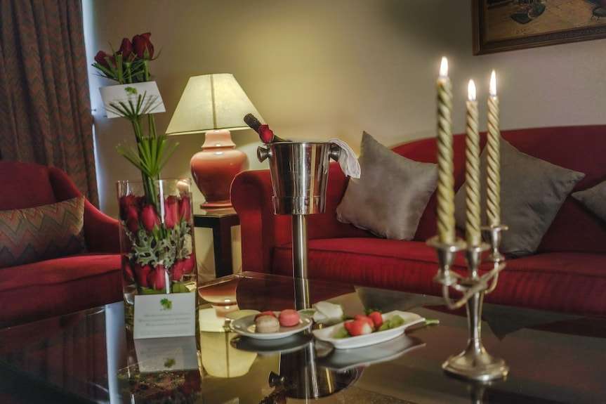 Luxury hotel room at Agadir Beach Club Hotel featuring red velvet furniture, lit candles, fresh roses, and a champagne bucket