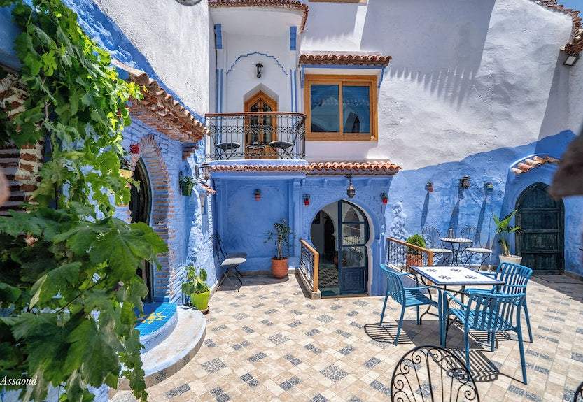 Alhambra Ryad & Spa blue and white courtyard with tiled floor, wrought iron and blue metal chairs, and potted plants