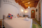 Alhambra Ryad & Spa bedroom with wooden ceiling, white walls, colorful floral cushions, green tiled floor, and wooden door