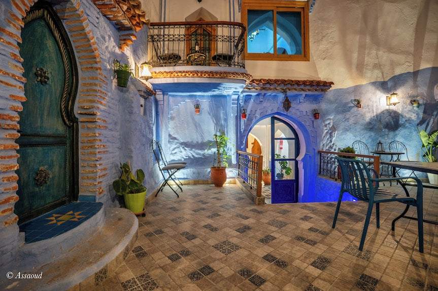 Alhambra Ryad & Spa outdoor terrace with blue painted walls, decorative archways, tiled floor, and wrought iron furniture