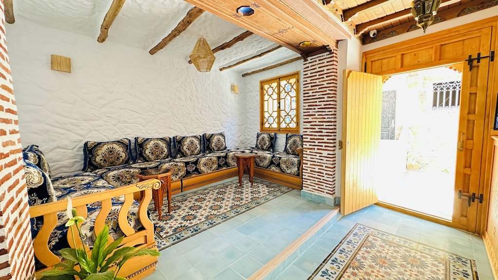 Alhambra Ryad & Spa traditional Moroccan lounge with wooden beams, patterned cushions, brick accents, and tiled floor