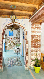 Alhambra Ryad & Spa Moroccan riad interior with tiled archway, patterned floor tiles, brick walls, and wooden ceiling