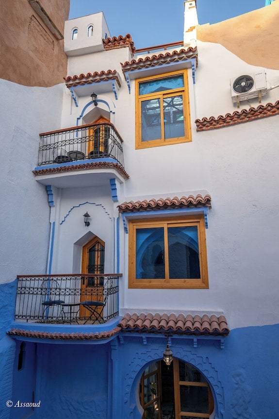 Alhambra Ryad & Spa exterior white and blue Moroccan riad with wooden framed windows, balconies, and terracotta roof tiles
