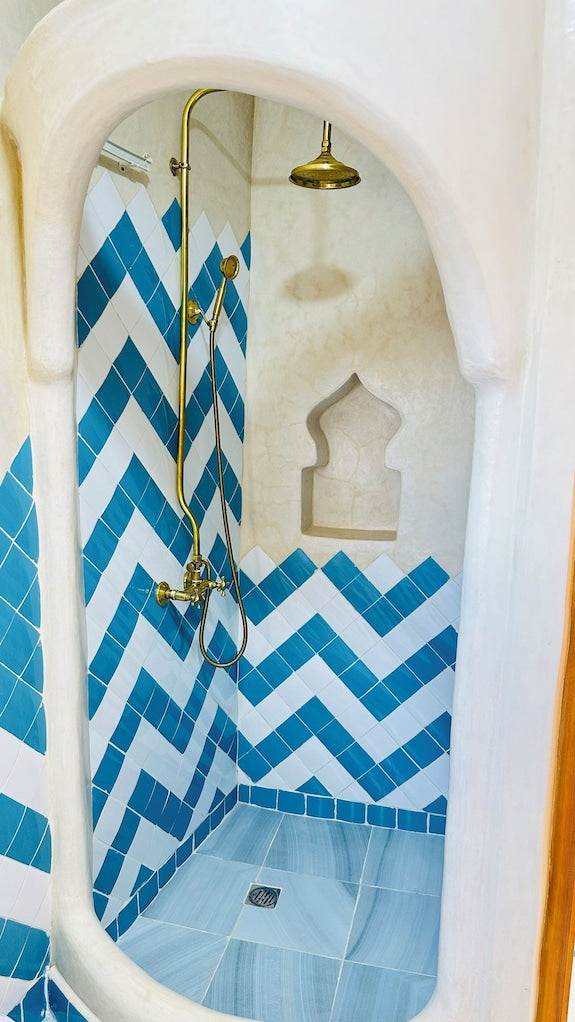 Alhambra Ryad & Spa Moroccan-style shower with blue and white chevron tiles and brass fixtures in a curved niche