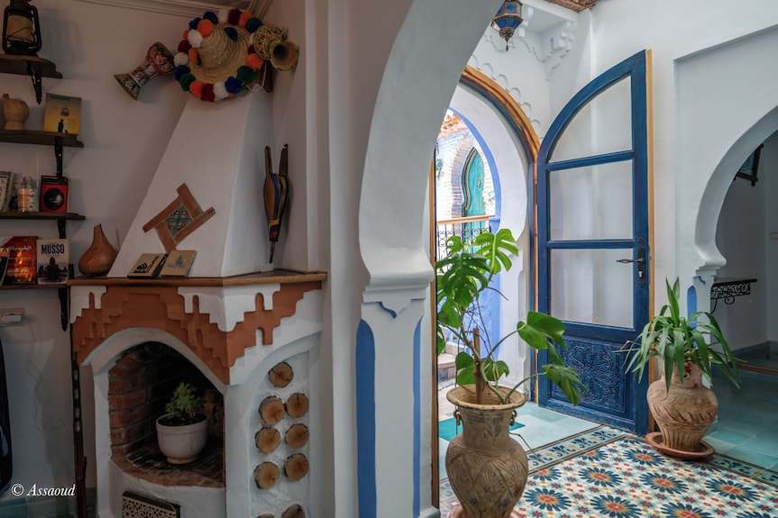 Alhambra Ryad & Spa airy interior with white walls, blue door, intricate tile floor, arched doorways, and potted plants