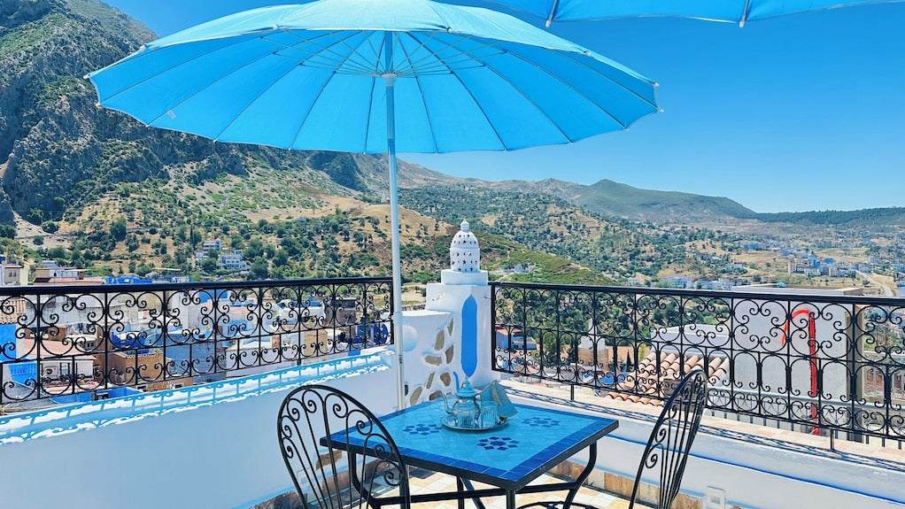 Alhambra Ryad & Spa outdoor terrace with blue umbrella, mosaic table, wrought iron chairs, mountain view