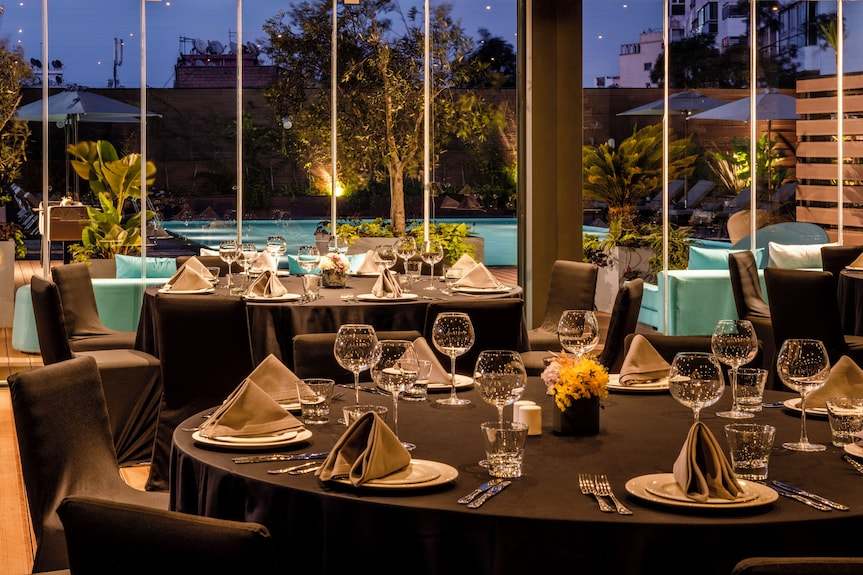 Barcelo Anfa Casablanca hotel dining room with black tables, folded napkins, glassware, and pool views
