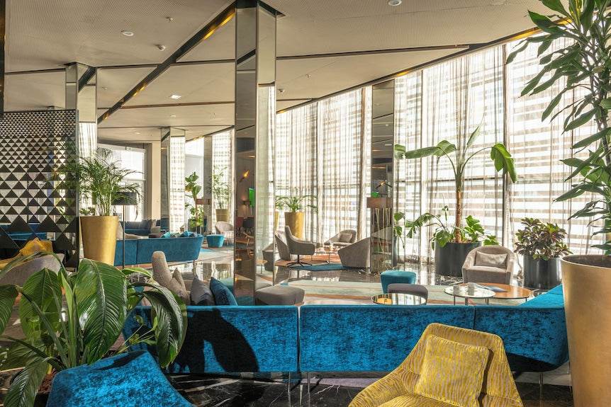 Barcelo Anfa Casablanca hotel lobby with vibrant blue sofas, mirrored walls, indoor plants and contemporary seating