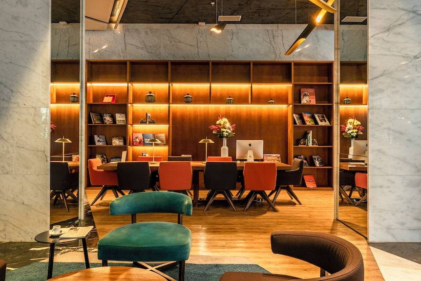 Barcelo Anfa Casablanca hotel lobby with warm wood shelving, green velvet chairs, and modern workspace seating