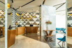 Barcelo Anfa Casablanca hotel reception with warm wood desks, marble pillars, geometric patterned wall and floral arrangements