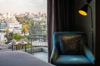 Barcelo Anfa Casablanca hotel room with teal velvet armchair, patterned cushion, balcony view and breakfast table
