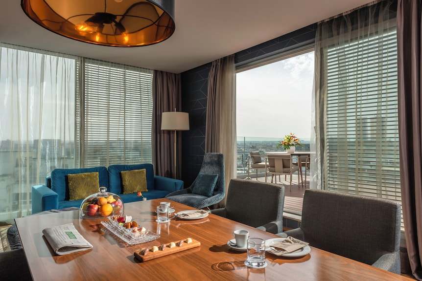 Barcelo Anfa Casablanca hotel suite with blue sofa, wooden dining table, ocean view, and private terrace