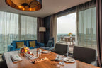 Barcelo Anfa Casablanca hotel suite with blue sofa, wooden dining table, ocean view, and private terrace