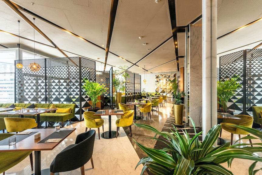 Barcelo Anfa Casablanca hotel restaurant with modern marble interior, green velvet chairs, plants and geometric screens