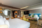Barcelo Anfa Casablanca hotel room with white beds, blue upholstered headboard, wood furnishings, desk, and modern decor