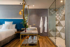 Barcelo Anfa Casablanca hotel room with white bedding, blue quilted headboard, marble vanity, robes, and glass shower
