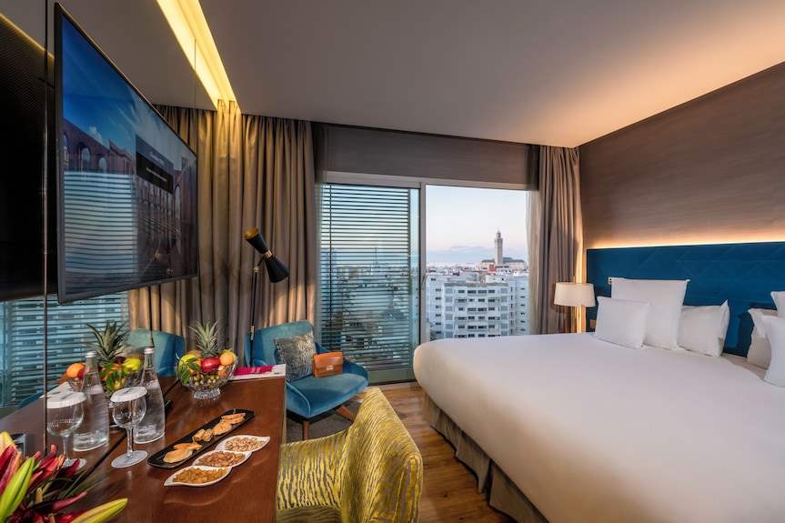 Barcelo Anfa Casablanca hotel room with white bed, blue headboard, modern furnishings, and city view