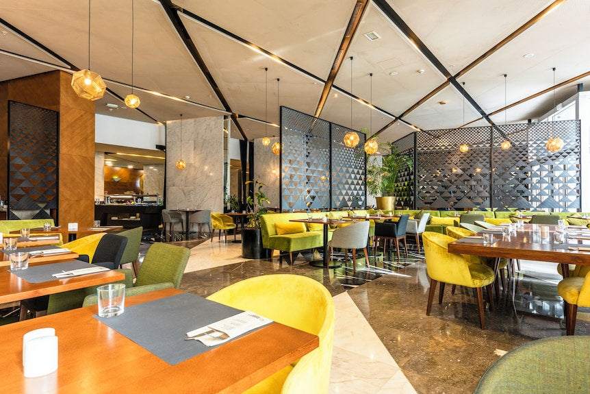 Barcelo Anfa Casablanca restaurant with modern dining tables, mustard yellow chairs, geometric screens, and pendant lights
