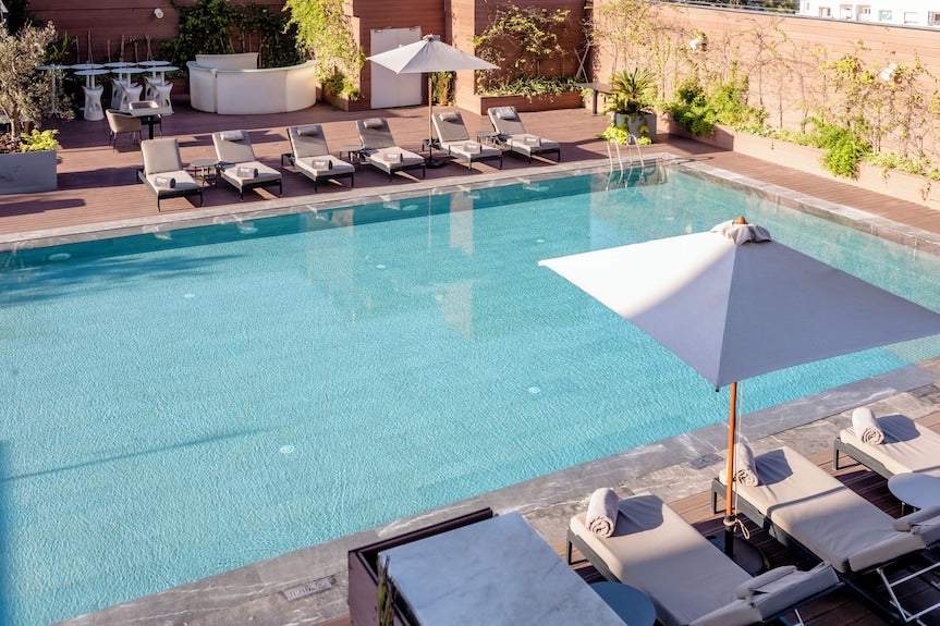 Barcelo Anfa Casablanca hotel outdoor swimming pool with turquoise water, sun loungers, umbrellas and plants