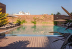 Barcelo Anfa Casablanca hotel outdoor swimming pool with wooden deck, sun loungers, umbrellas, and greenery
