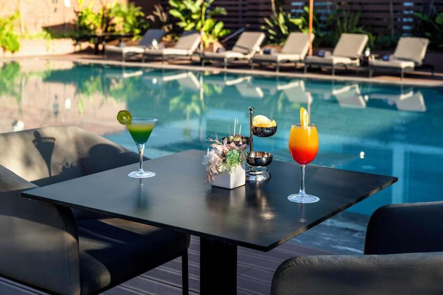 Barcelo Anfa Casablanca poolside bar table with black finish, colourful cocktails, and floral centerpiece