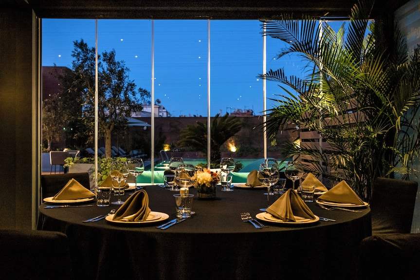 Barcelo Anfa Casablanca restaurant dining table with black linens, gold napkins, glassware, and pool view