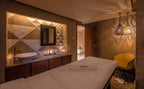 Barcelo Anfa Casablanca spa treatment room with beige massage table, marble geometric wall, sink, pendant lamps and yellow chair