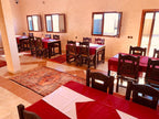 dining area at Berber Palace Hotel featuring wooden chairs, tables with red and white linens, and beige tiled floors