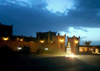 Berber Palace Hotel exterior at dusk with illuminated traditional Moroccan architecture and entrance sign glowing warmly