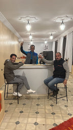 Berber Palace Hotel lounge area with three men seated on black stools at a white counter under bright ceiling lights