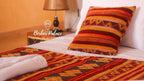 Berber Palace Hotel features a bed with orange and red striped Moroccan patterned pillow and matching runner on white linens