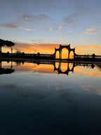 Berber Palace Hotel outdoor pool at sunset with ornate archway reflection and vibrant orange sky